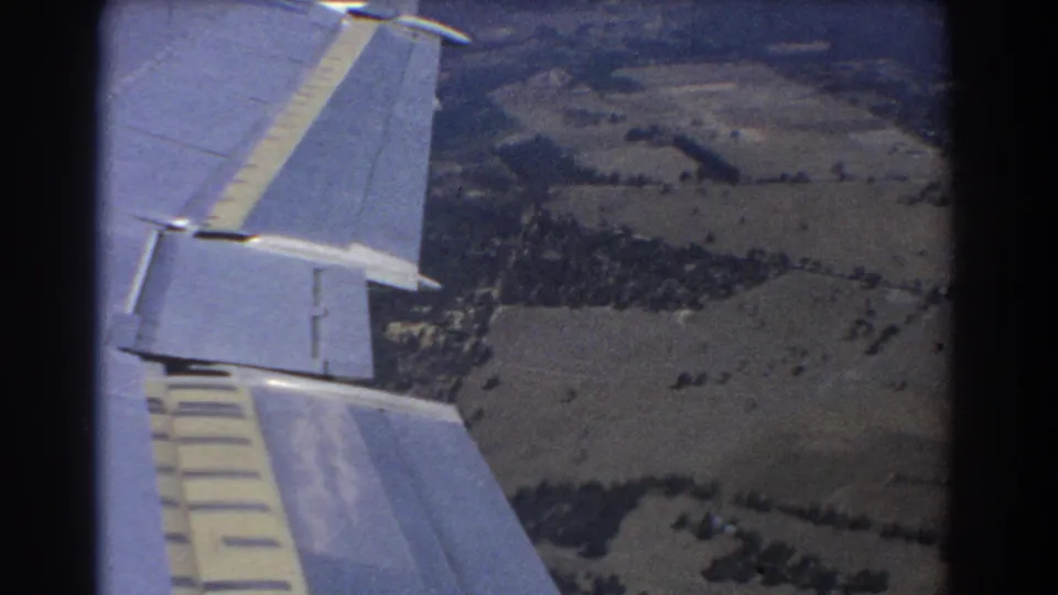 8mm frame showing the airplane wing from a passenger seat, with rural terrain below in the Perth flight footage.