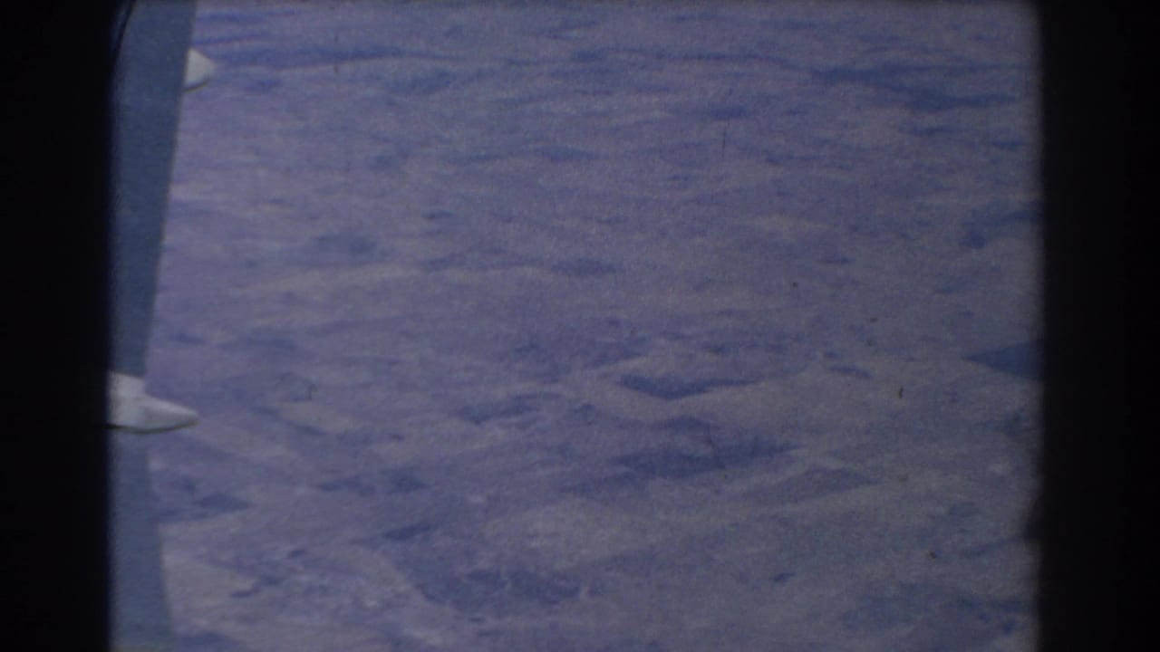 Aerial view of land through an airplane window with dark frame edges.
