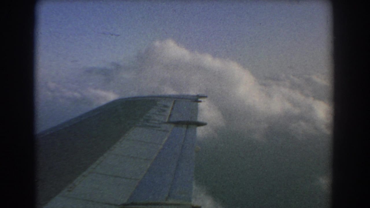 Aircraft wing crosses a layer of white and gray clouds.