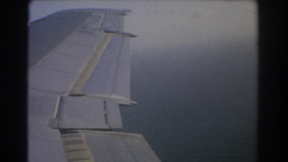 Passenger-seat view of the aircraft wing during a cloudy 1967 flight over Perth, with soft grain and dark frame edges.