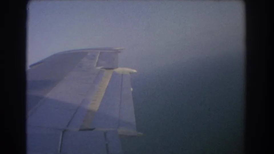 The airplane wing angles across a hazy ocean view in this 1967 Perth-area home-movie travel shot.