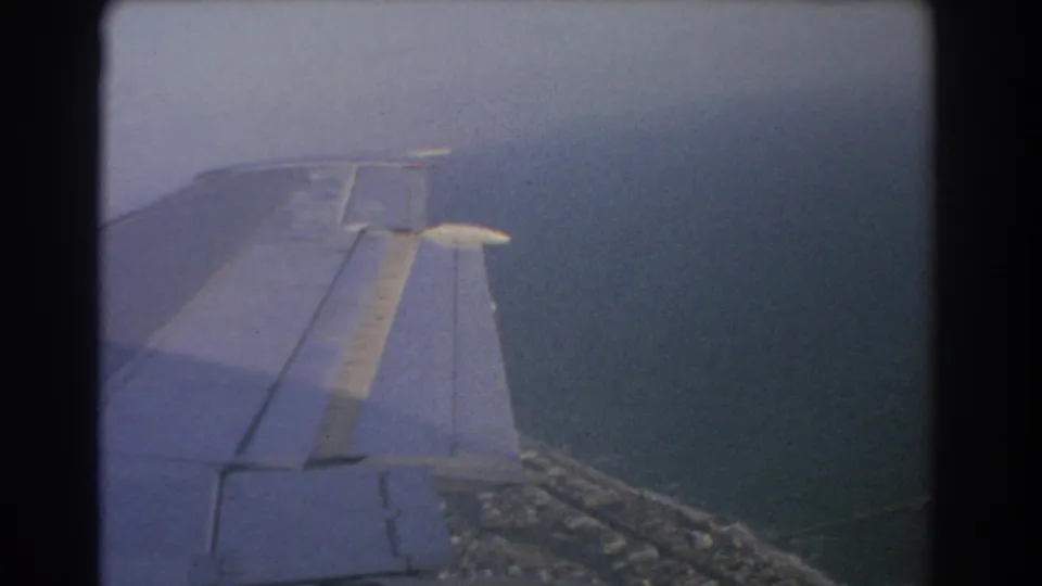 Passenger-window view of an airplane wing as coastline appears below during a 1967 flight near Perth, Australia.