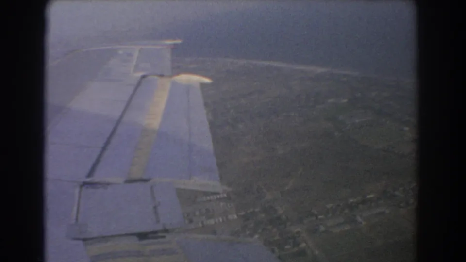 Passenger view from a 1967 8mm film, with the airplane wing over Perth's coastal urban landscape.