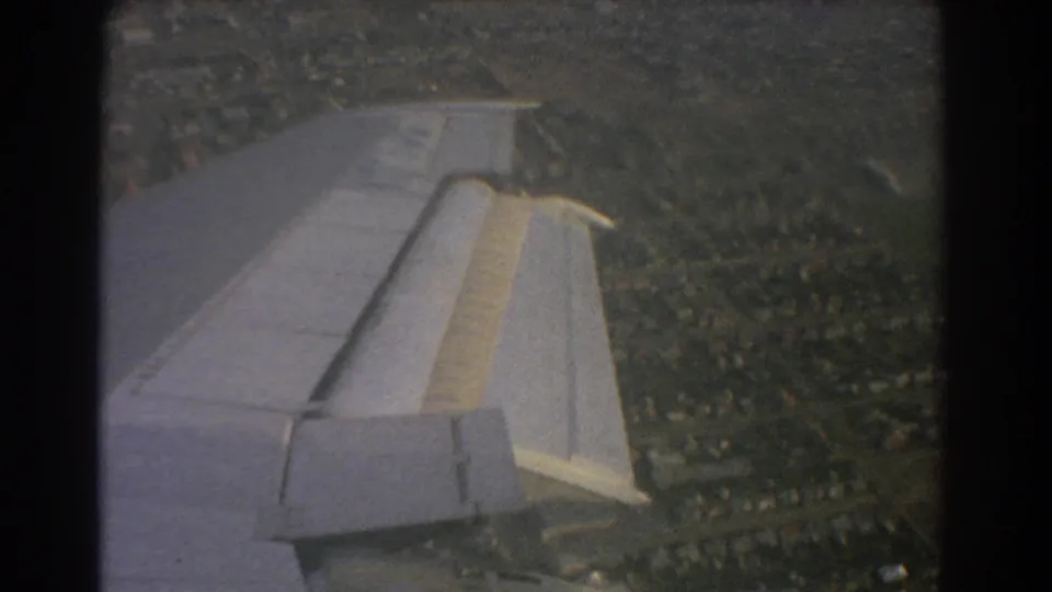 Perth-area 1967 home-movie frame with the airplane wing above a denser suburban pattern and visible 8mm frame edges.