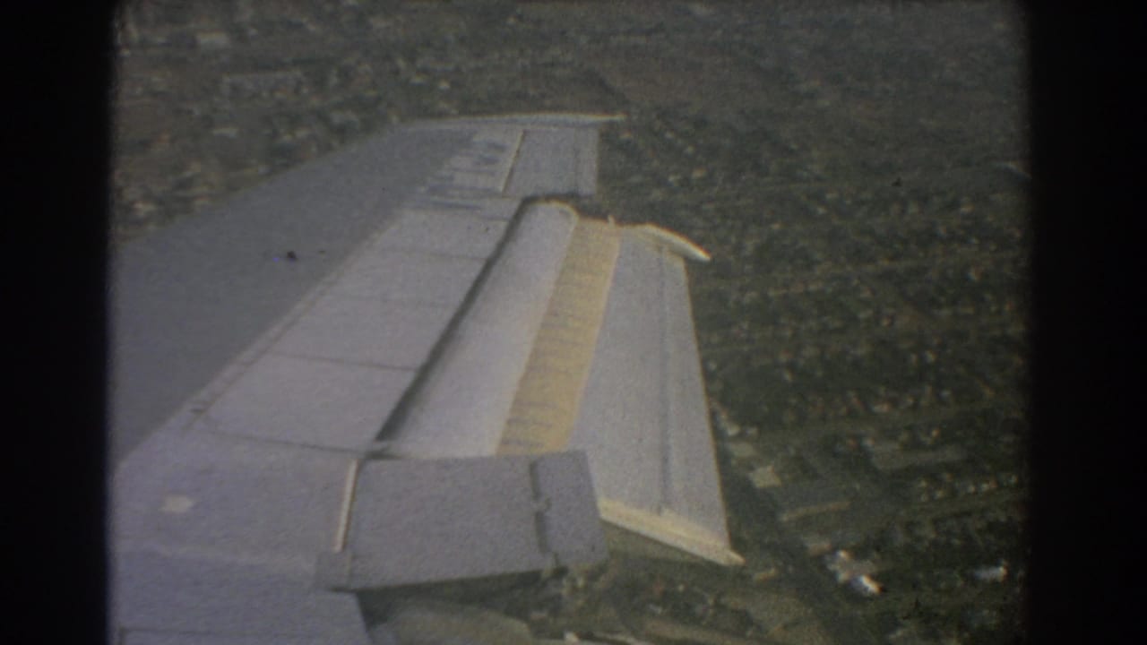 Aircraft wing and flap area over a dense suburban view.