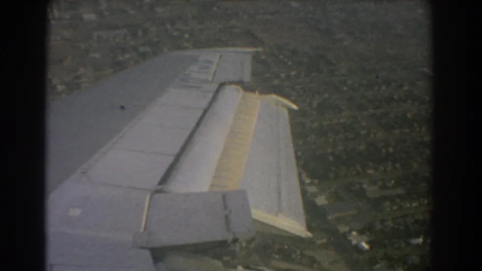 Passenger-window view of the aircraft wing above Perth-context suburbs, with the flap section visible on the trailing edge.