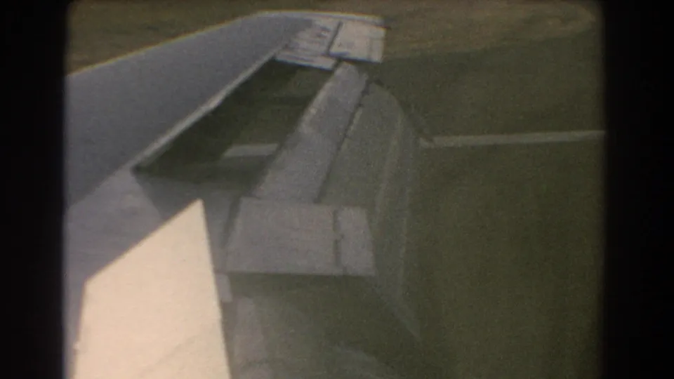 1967 Perth-context airplane wing view with flaps extended as the aircraft descends close to runway-side ground.