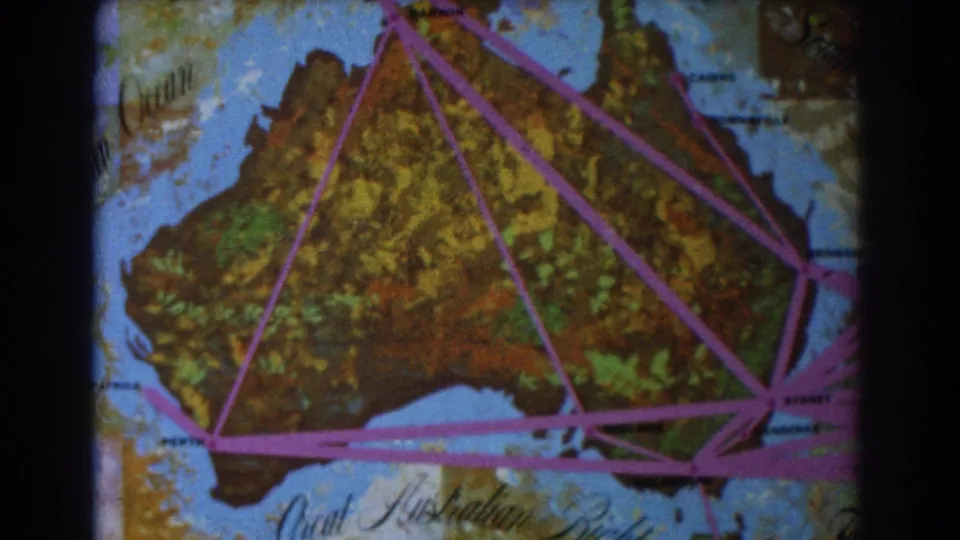 1967 8mm map shot with Australia filling the frame, crossed by purple travel-route lines and surrounded by blue ocean.