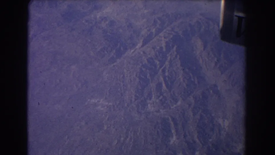 1967 8mm frame showing a purple-blue Earth-like surface or projected space view with dark gate edges and visible film wear.