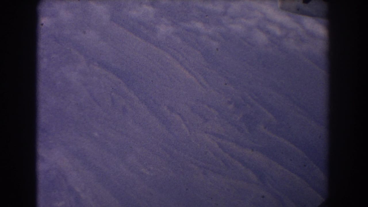 1967 8mm home-movie frame showing rugged mountain ridges near Sydney, Australia, with faded purple-blue color and gate edges.