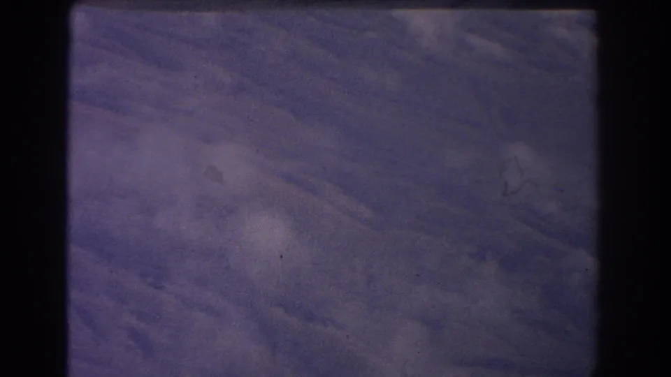 Purple-blue textured surface fills the frame, with soft light variation, grain, and dust in the 1967 Sydney 8mm source.