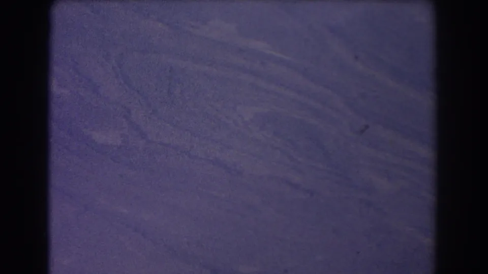 1967 8mm aerial footage over Australian terrain, showing muted blue-purple land textures and visible film grain.