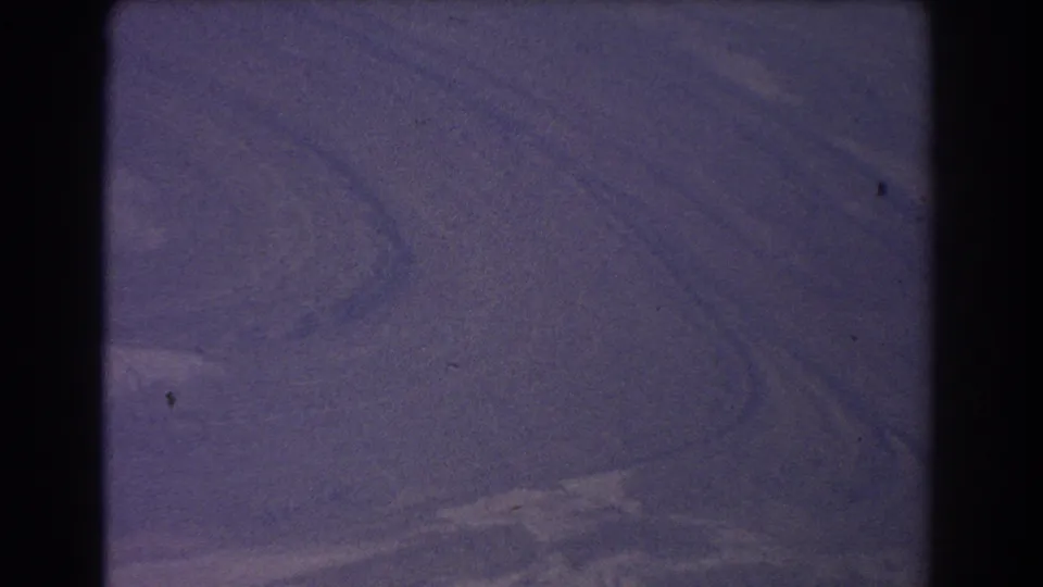 1967 8mm aerial view over Australian landscape, with muted land patterns, soft haze, and aged blue-purple film color.