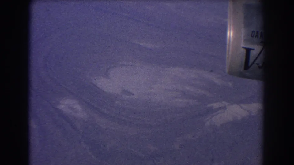 1967 Sydney Australia 8mm frame showing a downward abstract view of textured land or water patterns, with a cropped container at right.