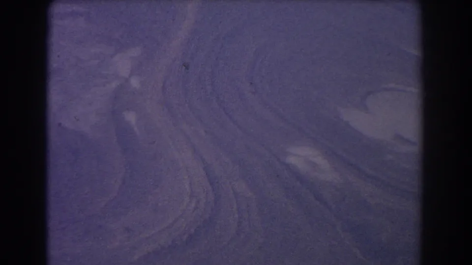 1967 8mm home-movie frame from the Sydney Australia clip showing broad, ambiguous swirling terrain or water patterns from above.