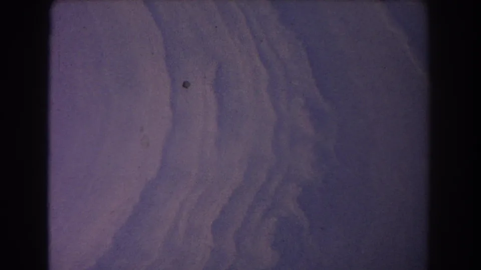1967 Sydney-labeled 8mm frame showing a soft purple-blue aerial view of ridged abstract terrain or cloud-like surface.