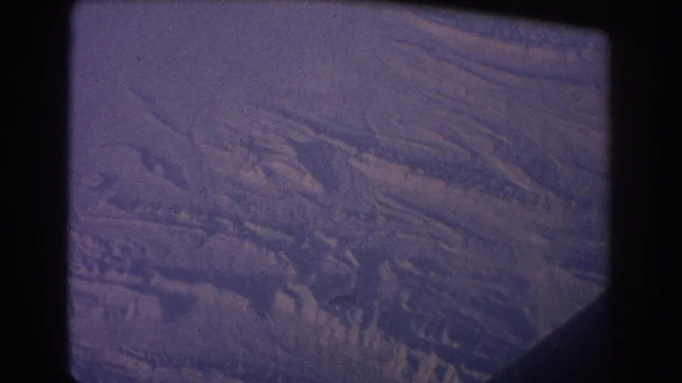 1967 airplane-window view over the Sydney, Australia area, showing violet cloud cover and textured ground far below.
