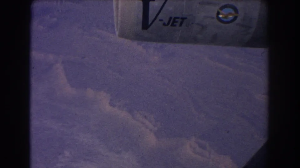 1967 8mm view from a passenger aircraft showing the wing with V-JET lettering above clouds and terrain near Sydney, Australia.