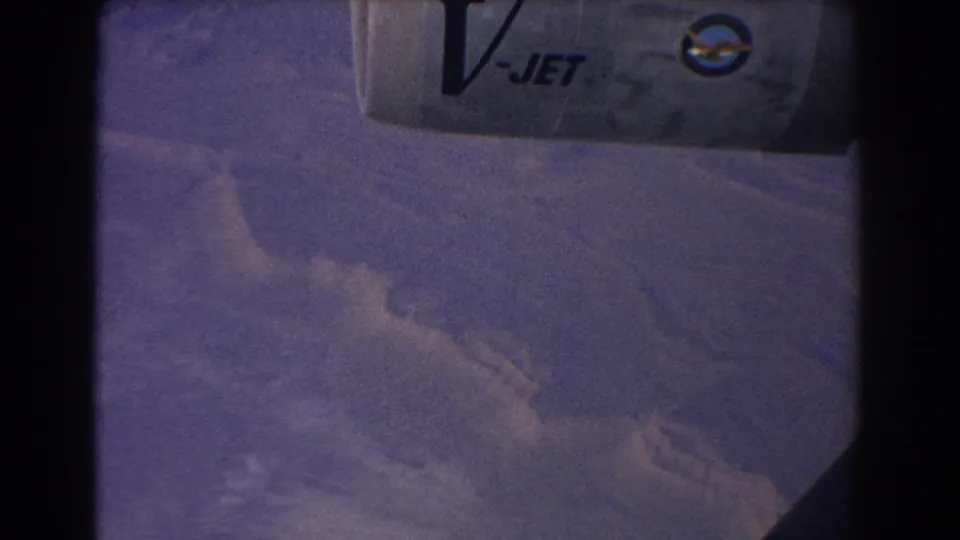 Passenger-window view from 1967 showing a V-JET-marked aircraft wing over violet clouds and distant Australian terrain.