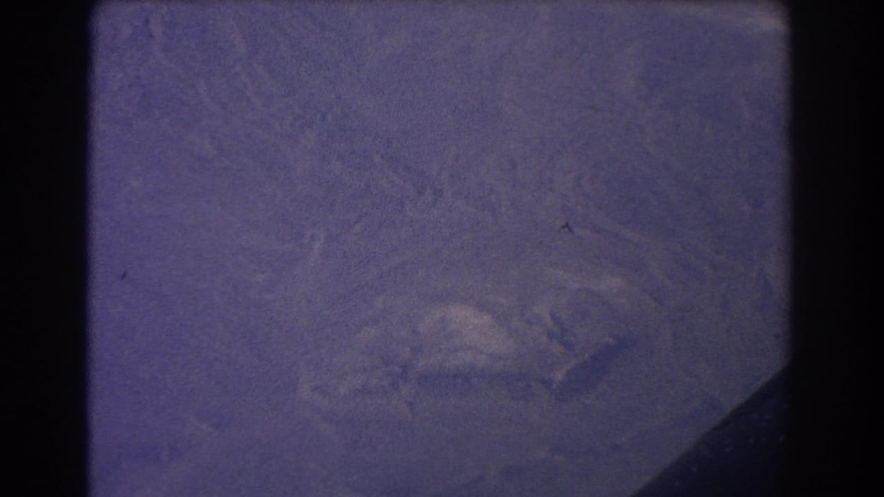 Purple-tinted aerial view of rugged terrain beside a dark frame edge.