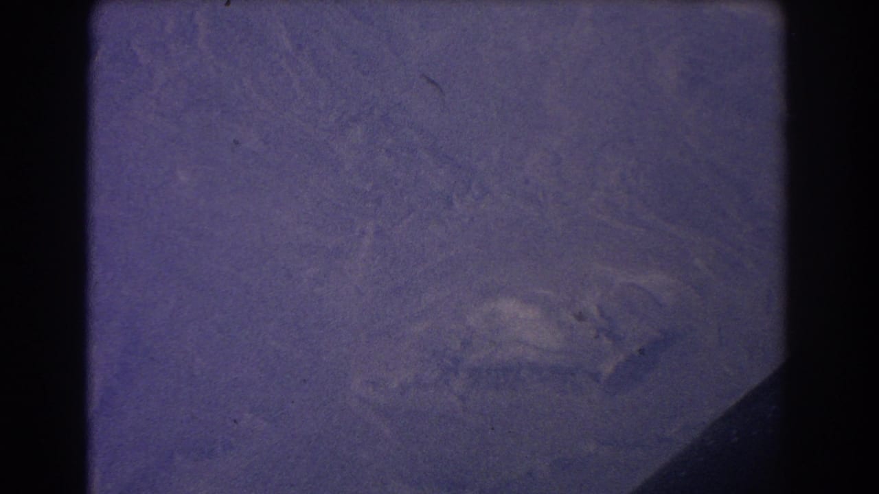 Hazy aerial landscape with pale terrain and a dark diagonal edge.