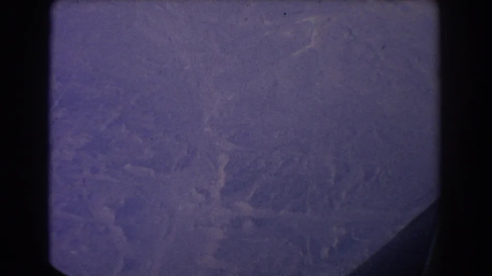 Sydney-area 1967 home-movie frame with distant wooded hills beneath an airplane window edge and visible 8mm grain.