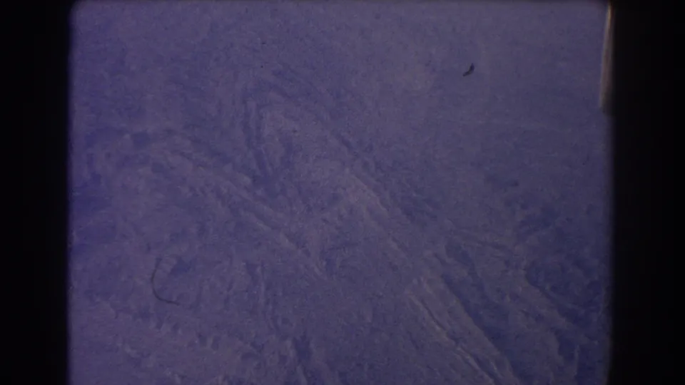 1967 8mm aerial view near Sydney with faint terrain patterns, film scratches, dust and a dark frame edge.