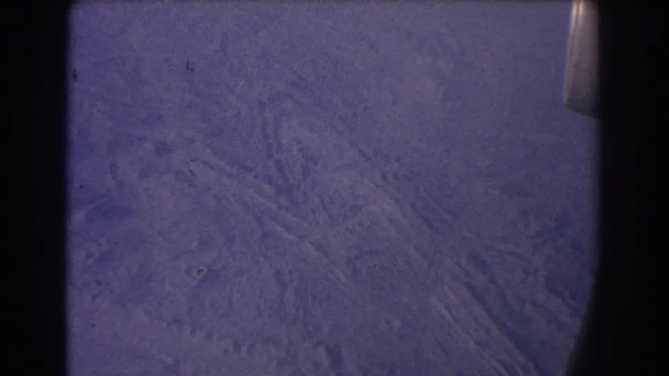 1967 8mm aerial view near Sydney, Australia, showing arid patterned ground through an airplane window.