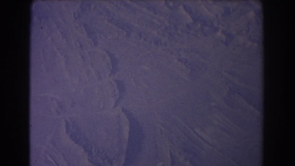 1967 airplane-window view over arid Australian terrain, with soft grain, dark gate edges, and muted purple color.