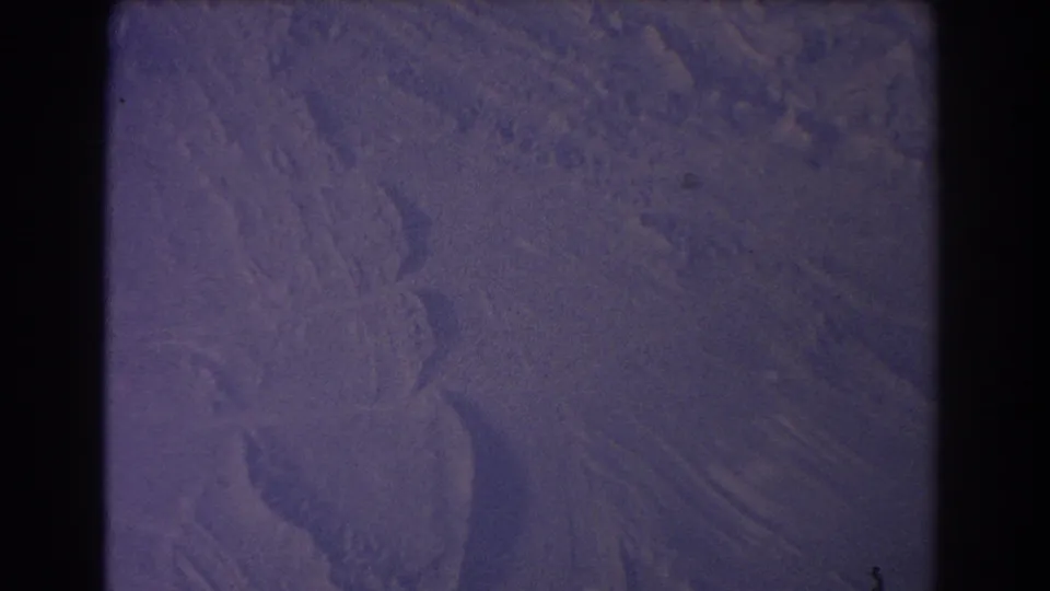 Cataloged 1967 8mm frame showing snowy terrain from an aircraft perspective, with purple color shift and visible film borders.