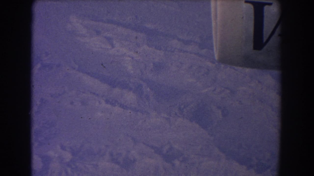 Purple-tinted aerial view of dry terrain partly blocked by a dark vertical frame edge.