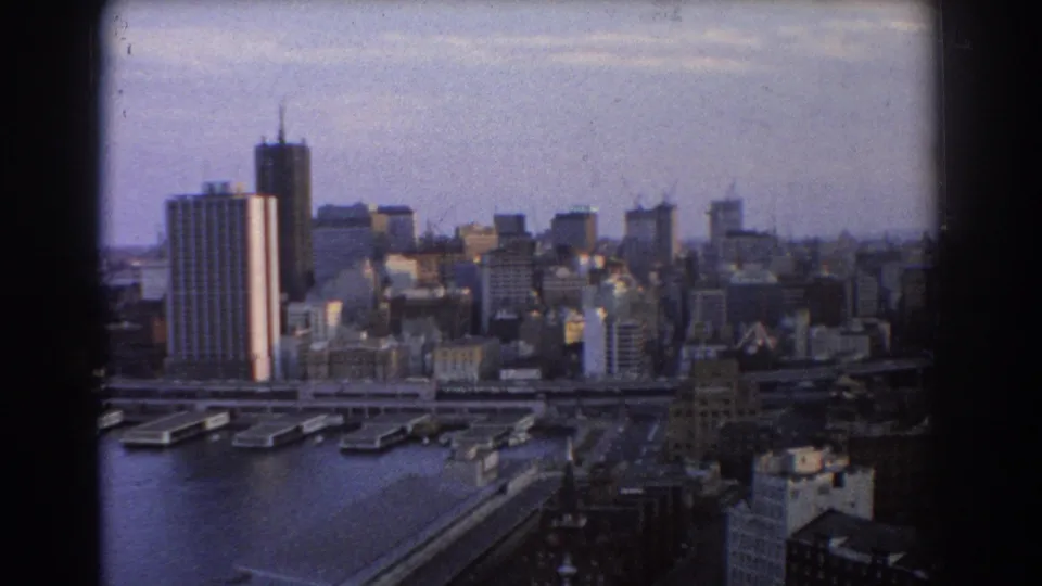 Late clip frame of 1967 Sydney, showing harbour wharves, city buildings, cranes, and a hazy skyline from above.