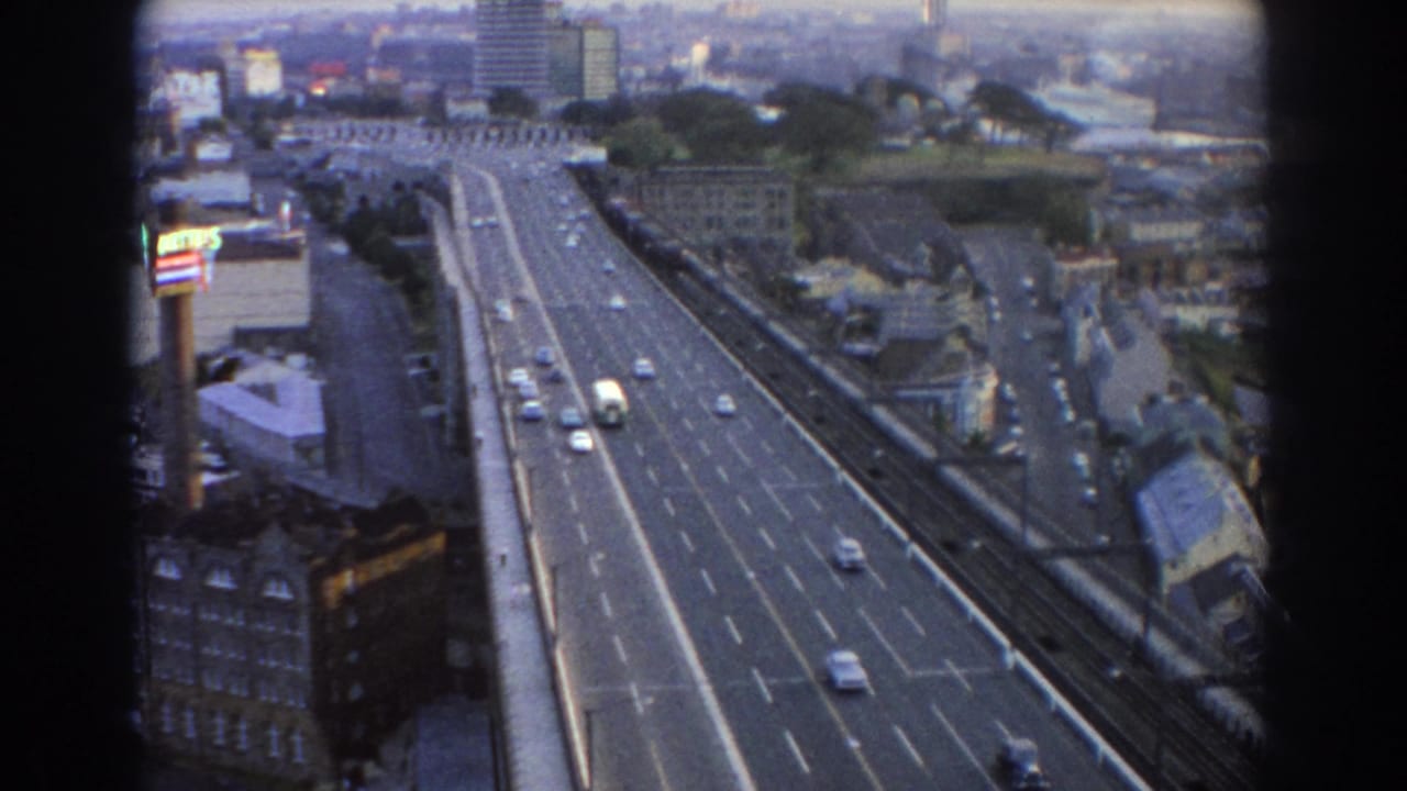 High view of road traffic with cars, buildings, and distant cityscape.