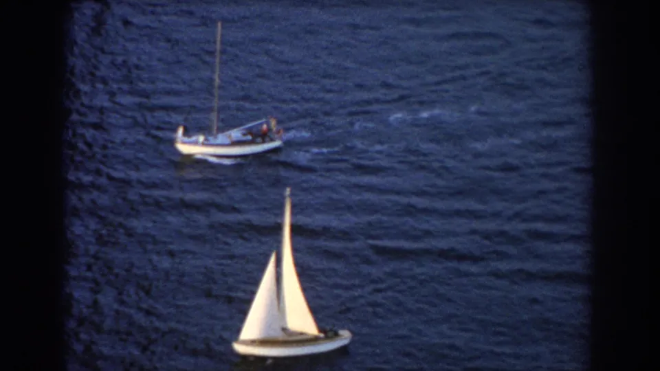A white-sailed recreational boat passes beneath a larger vessel in a 1967 Sydney-area ocean view.