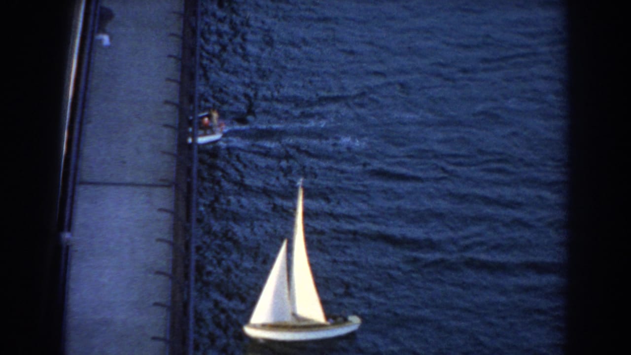 White sailboat near the lower frame with a small motorboat partly visible at upper left.