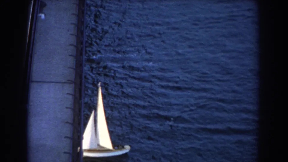 Final 1967 Sydney harbor frame showing the white sailboat partly lower left, framed by bridge structure and textured blue water.