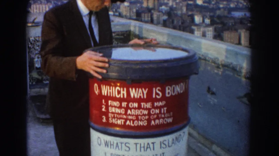 The home-movie frame shows a closer view of the 1967 Sydney lookout orientation table and the visitor's hands against the city view.