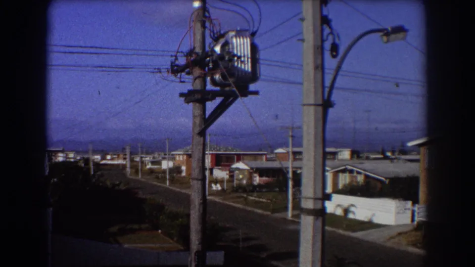 The wider view shows Sydney-area houses, poles and overhead lines beneath the perched kookaburra's wires.