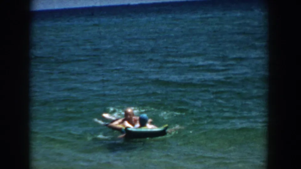 Two people appear to rest near a blue inflatable raft in a sunlit Florida lake, framed by dark 8mm scan edges.