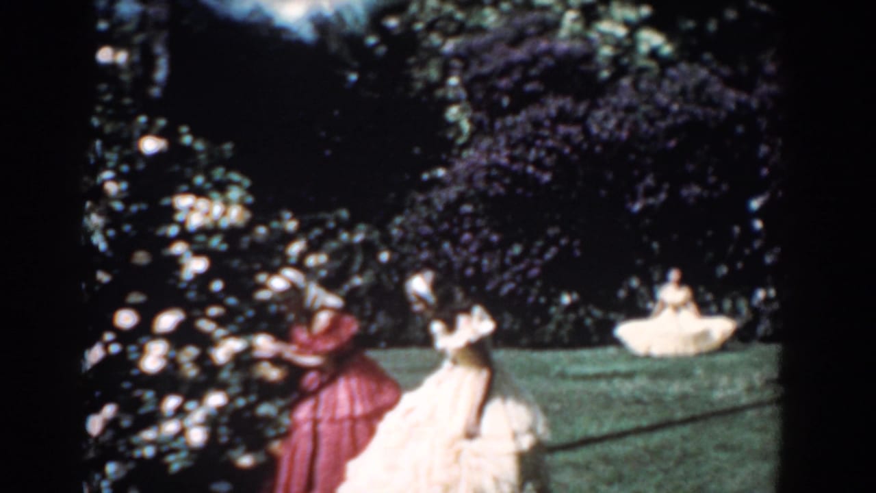 Women in flowing dresses stand near rose bushes in a 1957 Florida garden scene, with greenery and a seated figure in the background.