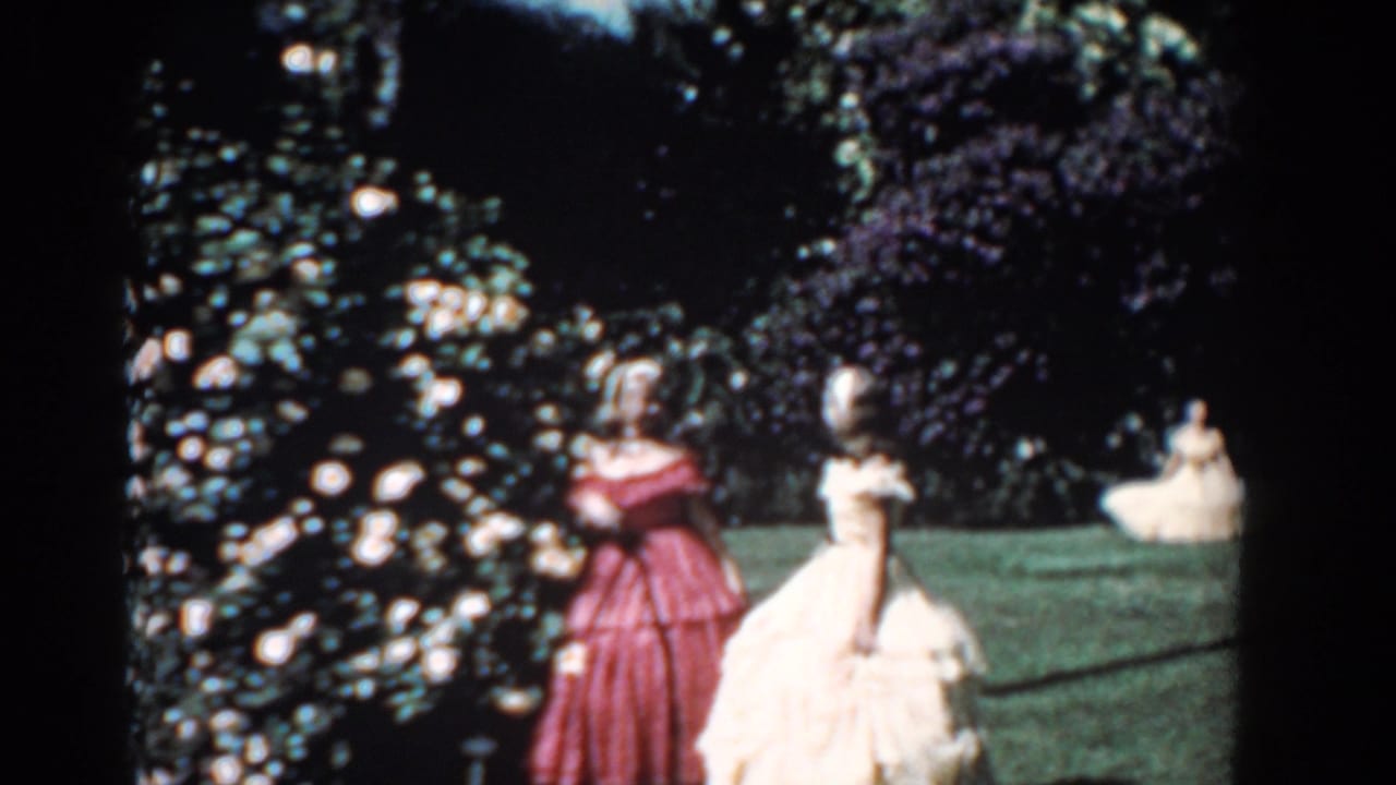 Women in red and cream dresses face the rose bushes in a 1957 Florida garden, with a seated woman visible across the grass.