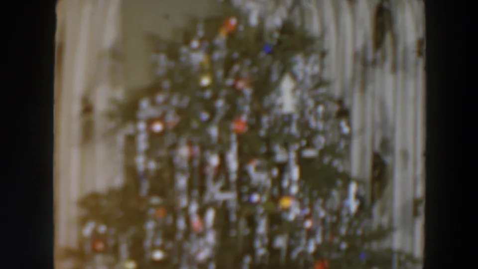 A decorated Christmas tree with red, blue, and yellow lights remains softly blurred in the closing 1957 frame.
