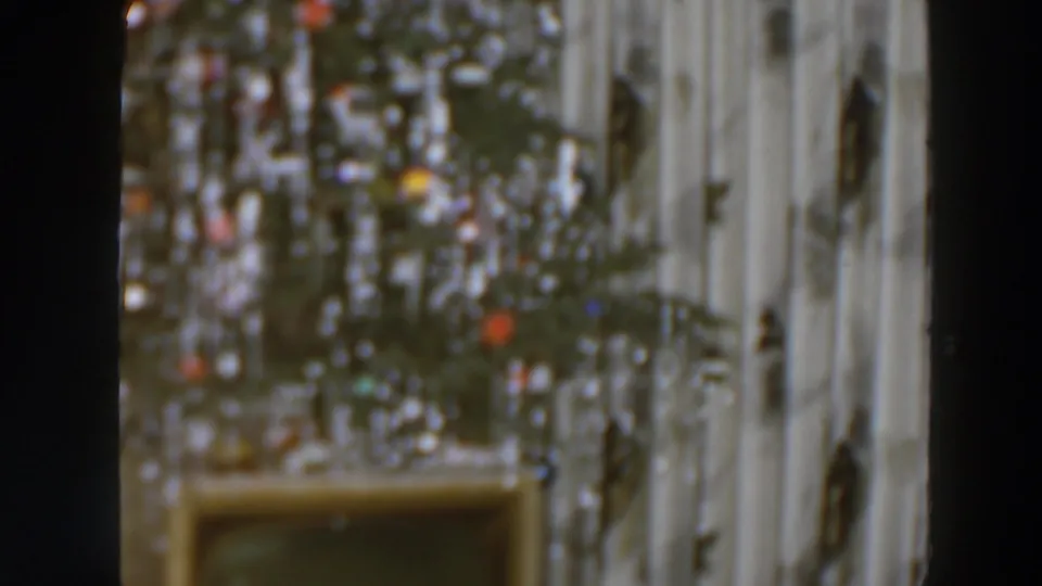 Decorated indoor Christmas tree in a likely Wheeling, Ohio home-movie frame from 1957, with visible grain, blur, and holiday lights.