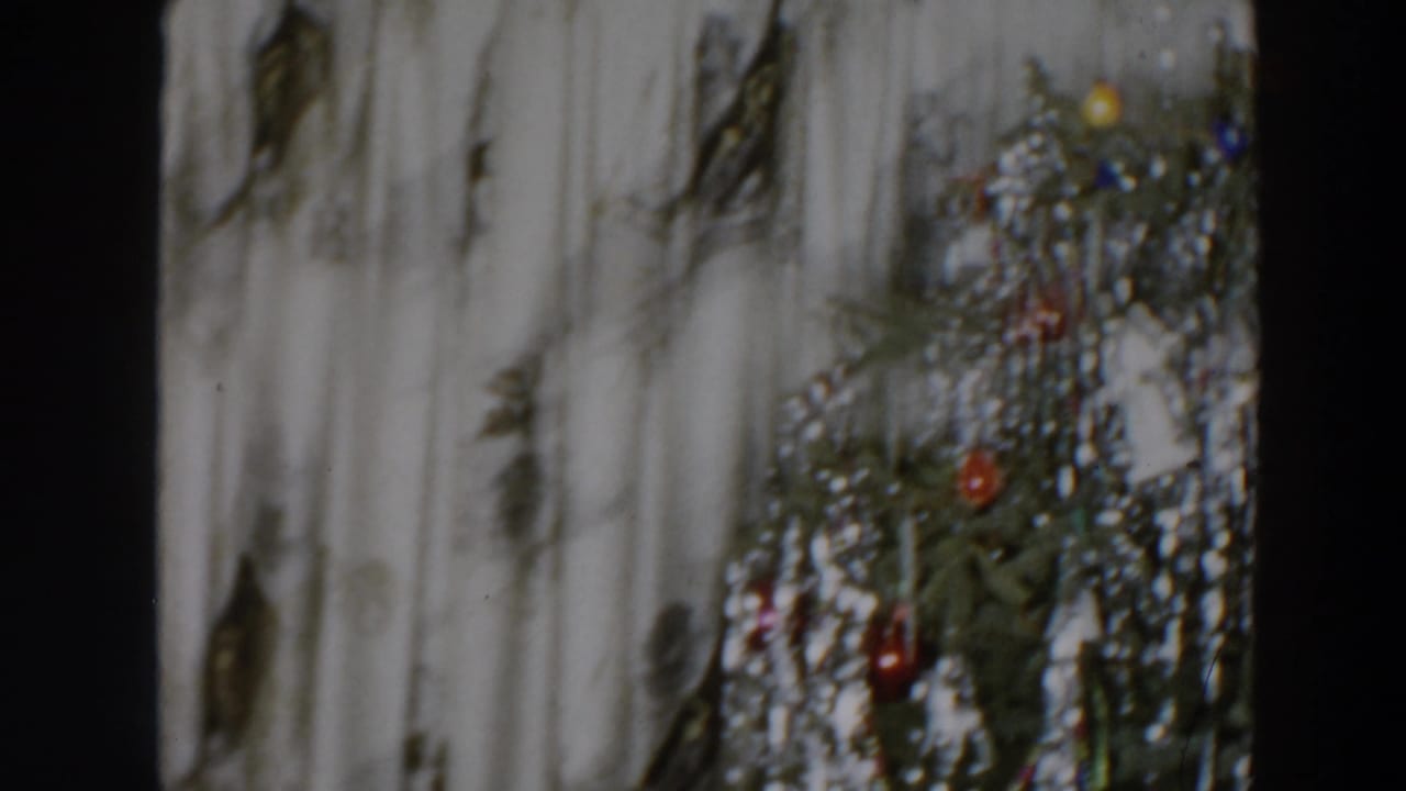 Decorated Christmas tree partly framed by curtains and dark film edges.