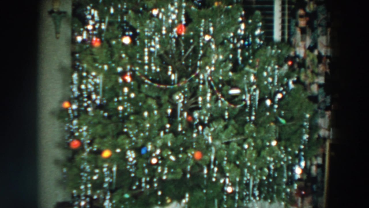 Decorated Christmas tree with colored lights and silver tinsel indoors.