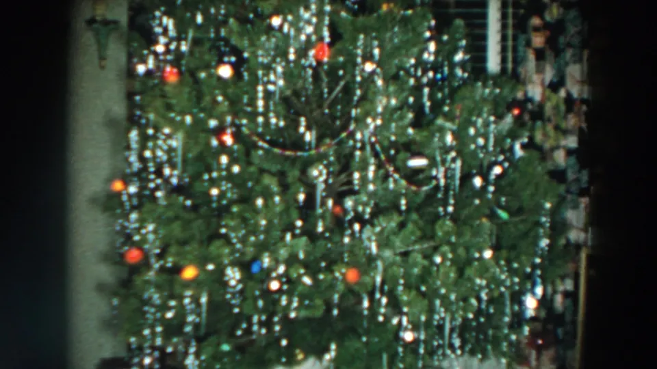 A decorated Christmas tree with colored lights and silver tinsel stands inside a Wheeling, Ohio home in 1957 footage.