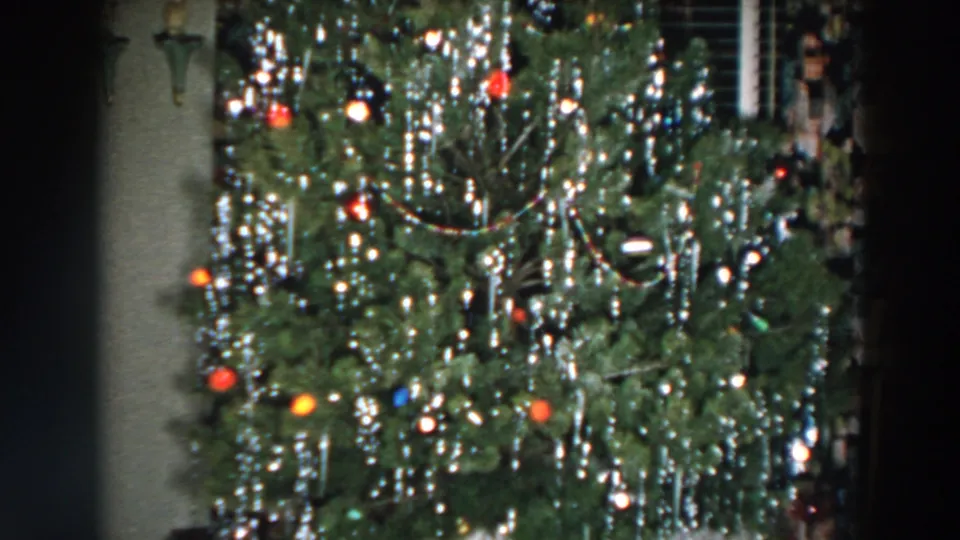 The final frame keeps the 1957 Wheeling holiday tree in close view, with silver tinsel, colored ornaments, lights, and curtains at the edge of the room.