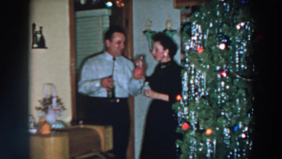 The adults appear to toast beside the decorated Christmas tree in the 1957 Wheeling, Ohio home-movie scene.