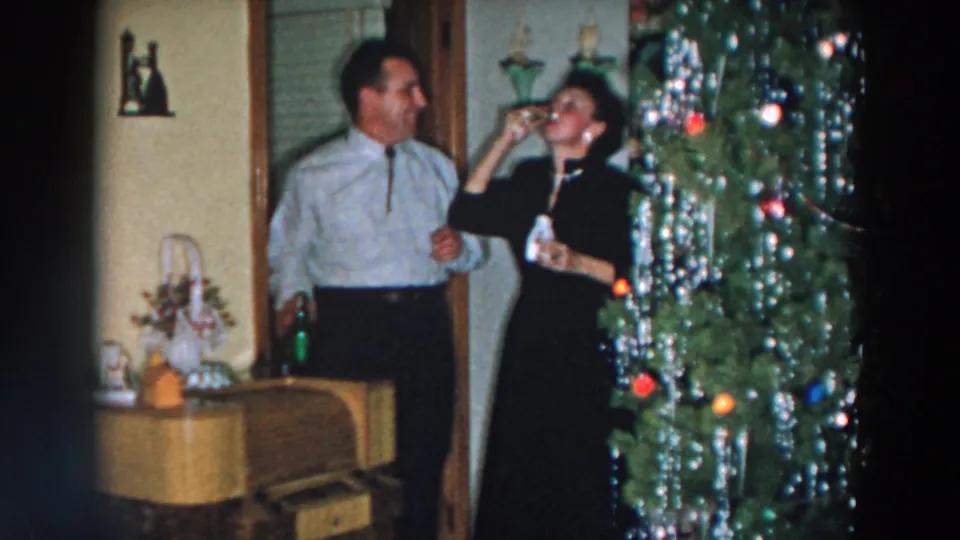 A woman drinks during a toast as a man looks on beside the Christmas tree in this 1957 Wheeling, Ohio home-movie scene.