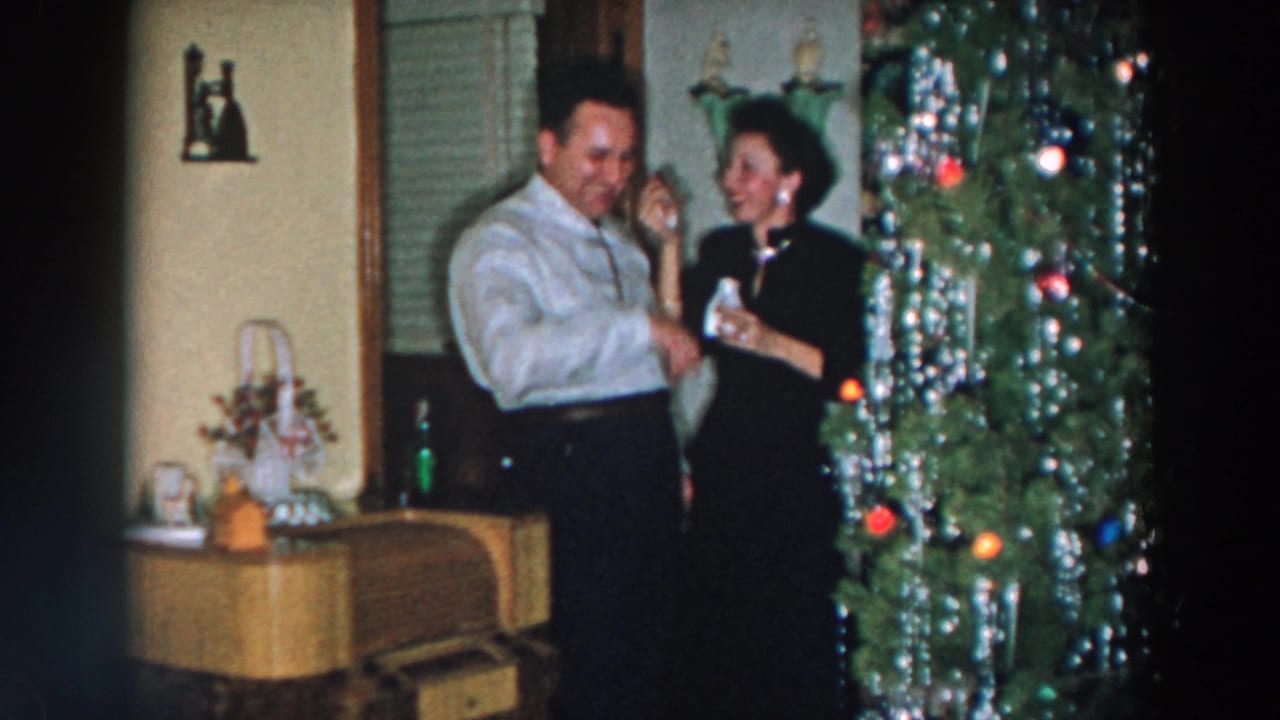 In 1957 Wheeling, Ohio home-movie footage, a man and woman stand near a tinsel-covered Christmas tree inside a private living room.